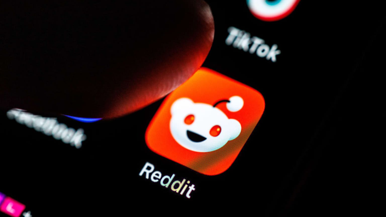 A finger hovering over the Reddit app icon on a smartphone screen, marking Friday August 14 2026 when Reddit shares jumped about 13 percent after S&P Dow Jones Indices said the social platform will join the S&P 500 on Tuesday August 18, replacing AvalonBay Communities