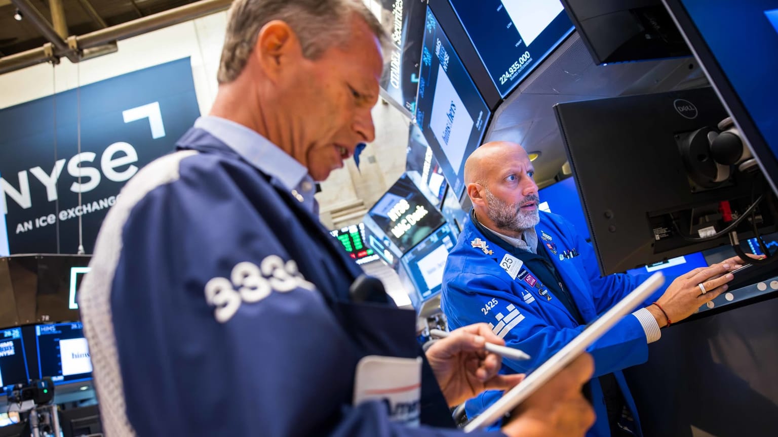 Two NYSE floor traders in blue jackets work a bank of screens on the New York Stock Exchange floor on Monday August 17 2026, the session when the S&P 500 faded from an open of 7,790.68 to close at 7,745.06 as West Texas Intermediate jumped about 3 percent on Iran and Oman headlines