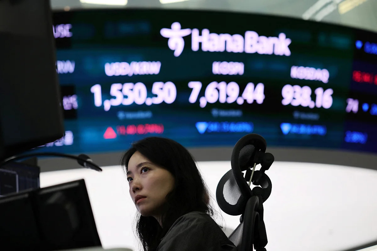 A trader watches the Hana Bank board in Seoul showing the won, KOSPI and Kosdaq as US stocks closed lower on Tuesday August 18 2026, when the S&P 500 finished at 7,691.76 and the Nasdaq Composite dropped 1.33 percent as semiconductors reversed Monday's memory-chip bid