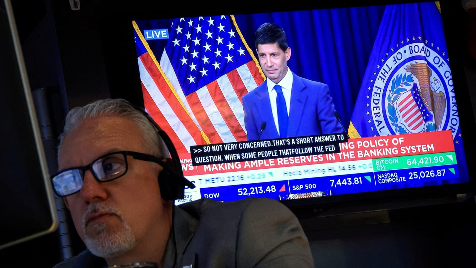 A floor trader in a headset watches a live Federal Reserve briefing on a screen that also shows the Dow, S&P 500, Nasdaq Composite and Bitcoin, used as the ThriveInMarkets evening-review inline image for Monday September 14 2026, when the 10-year yield tagged 5.012 percent, the S&P 500 closed 7,619.98, and markets priced about an 88 to 90 percent chance of a Wednesday hike