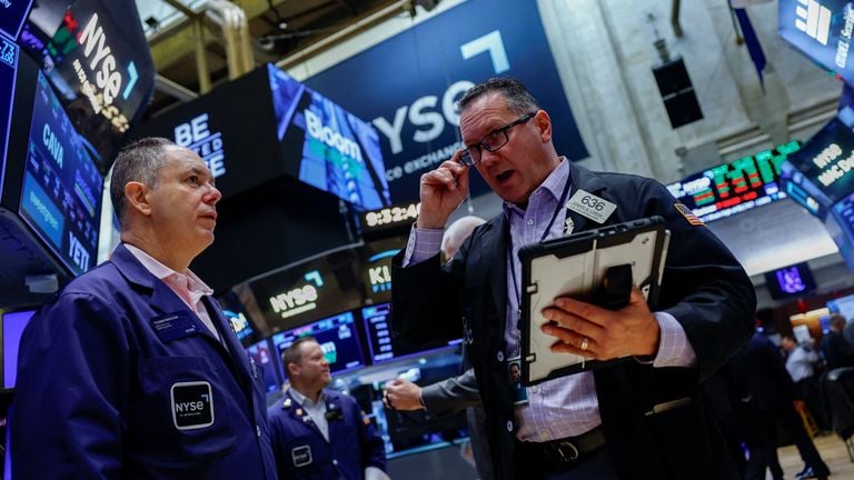 Two traders on the New York Stock Exchange floor talk beside quote screens, used as the ThriveInMarkets evening-review hero for Monday October 12 2026, when the S&P 500 closed 7,807.24 down 0.06 percent, the Nasdaq Composite closed 27,245.90 down 0.44 percent, and West Texas Intermediate last printed about 93.20 dollars after reversing the morning ceasefire fade