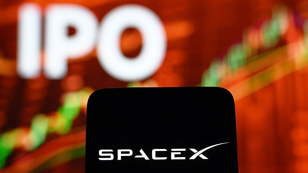 A smartphone displaying the white SpaceX logo is held in front of a glowing orange screen showing the word IPO and a rising candlestick stock chart, illustrating the June 12 2026 ThriveInMarkets morning analysis as SpaceX began trading on the Nasdaq under the ticker SPCX after pricing the largest initial public offering in history at 135 dollars per share, selling about 555.5 million shares to raise roughly 75 billion dollars at a valuation near 1.75 trillion dollars, with the deal reported to be about 3.3 times oversubscribed