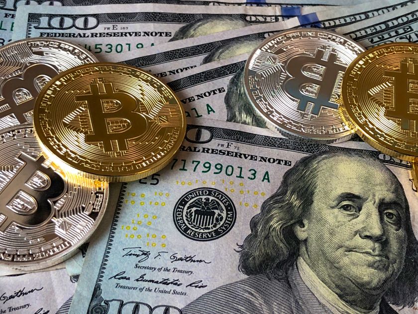 Gold-toned Bitcoin coins resting on US dollar bills under warm light, illustrating the June 19 2026 ThriveInMarkets morning analysis as Bitcoin slipped below 63,000 dollars to about 62,567 dollars on a hawkish Federal Reserve, spot gold eased to about 4,157 dollars after recovering above 4,300 on Thursday, WTI crude hovered near 75 dollars close to three-month lows as the US-Iran deal unwinds the war premium, and US stock and bond markets stayed shut for the Juneteenth holiday with the S&P 500 last at 7,500.58 and the Nasdaq at 26,517.93