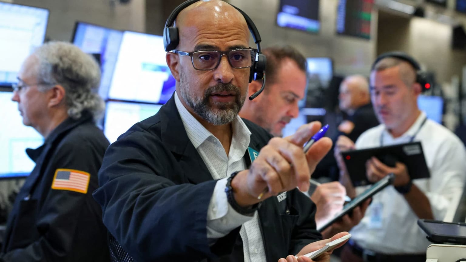 A New York Stock Exchange floor trader in a headset points while colleagues work tablets behind him, used as the ThriveInMarkets morning analysis inline image for Monday September 14 2026, when overnight E-mini S&P 500 futures sat near 7,610 against Friday's 7,656.98 cash close, Nasdaq-100 futures were down about 1.2 to 1.5 percent, and West Texas Intermediate jumped toward 103 dollars on confirmed Saudi pipeline damage