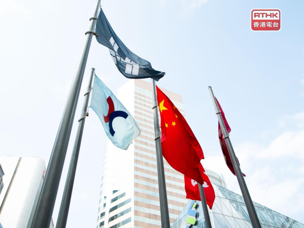 Flags of China, Hong Kong and financial houses fly on poles in front of a glass tower in Hong Kong, used as the ThriveInMarkets morning analysis hero for Friday October 2 2026, when the Hang Seng last printed about 23,900 down about 3 percent after the National Day break, overnight E-mini S&P 500 December futures sat near 7,744 against Thursday's 7,666.45 cash close, and September nonfarm payrolls are due at 12:30 UTC