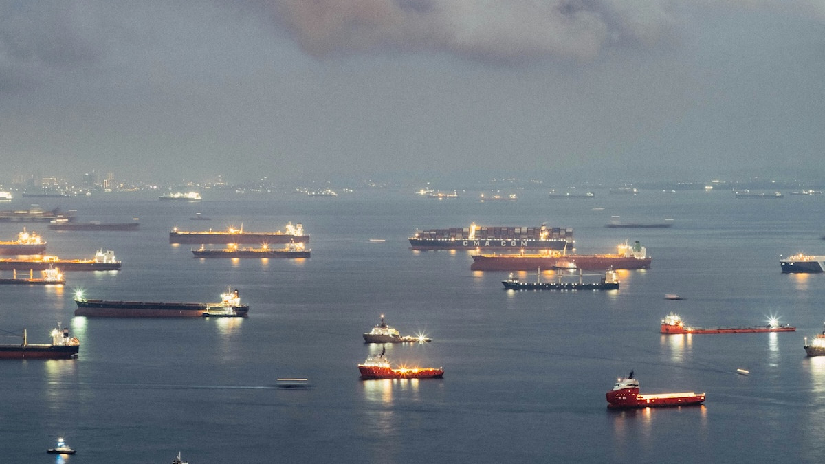 Tankers and container ships at dusk with deck lights on, used as the ThriveInMarkets morning analysis hero for Wednesday October 7 2026, when Bitcoin last printed about 84,214 dollars after oil jumped on tanker attacks, Brent sat back above 100 dollars, WTI last printed about 89.90 dollars, and FOMC minutes are due at 18:00 UTC