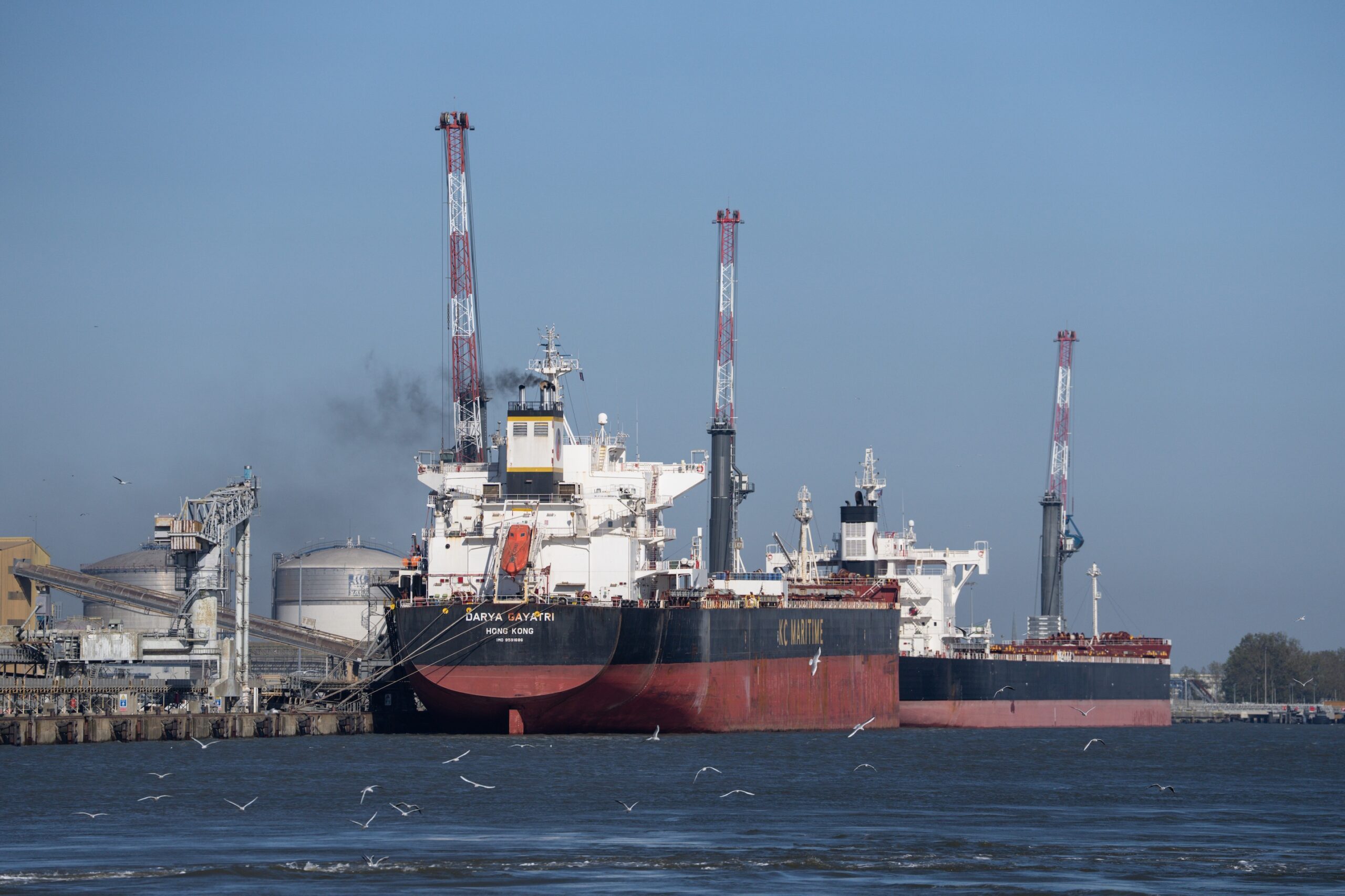 The Hong Kong-flagged tanker Darya Gayatri and a second tanker sit at a dock under red-and-white cranes, used as the ThriveInMarkets morning analysis inline image for Friday October 16 2026, when West Texas Intermediate last printed about 97.38 dollars after the IEA said it would complete remaining emergency oil releases