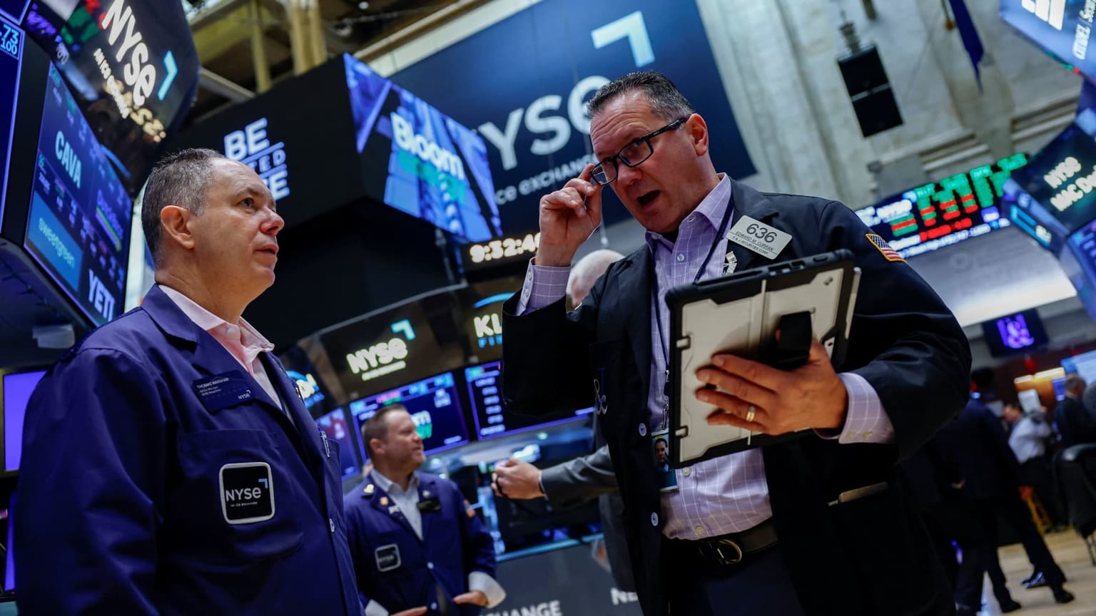 NYSE floor traders in blue jackets talk beside quote screens at the New York Stock Exchange, used as the ThriveInMarkets week-ahead hero for October 5 to 9 2026, when Wednesday's FOMC minutes recap the September 15-16 hike after Friday's 29,000 payrolls print, Monday's ISM services is seen near 55.0, and PepsiCo reports Thursday before the open