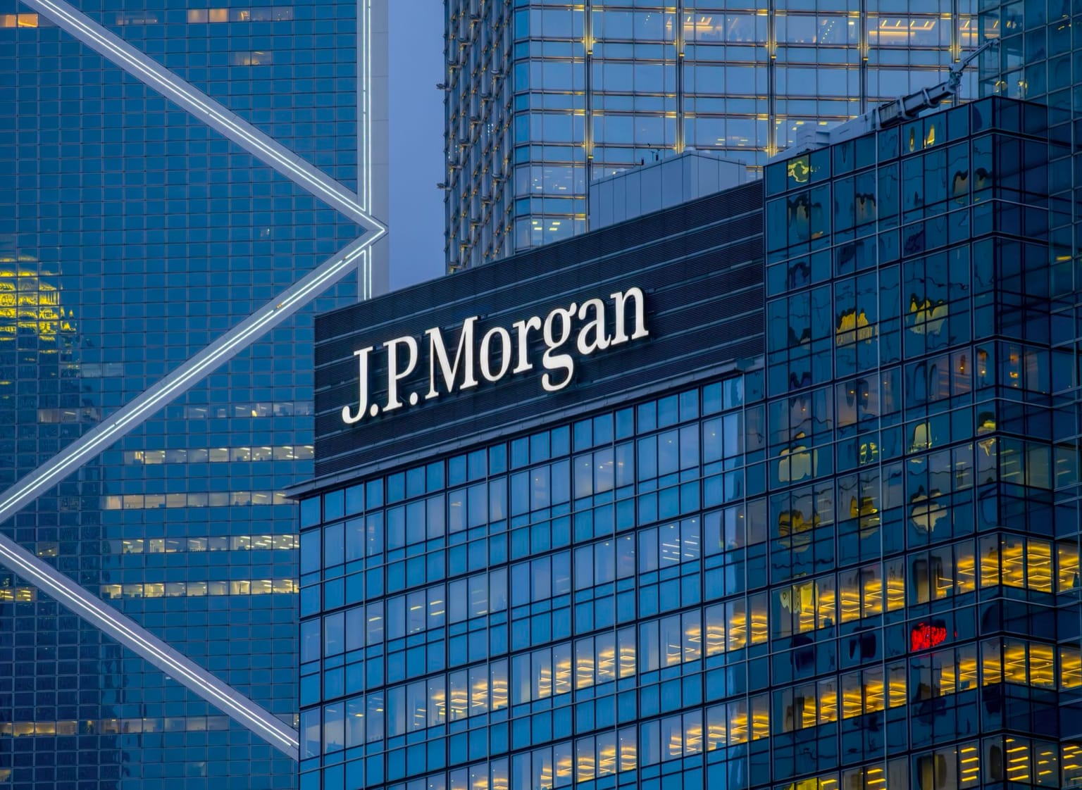 J.P. Morgan headquarters glass tower with the bank's name lit at dusk, used as the ThriveInMarkets week-ahead hero for October 12 to 16 2026, when JPMorgan, Goldman Sachs, Citigroup and Wells Fargo report Tuesday before the open and September CPI lands Wednesday at 12:30 UTC as the last inflation print before the October 27-28 FOMC